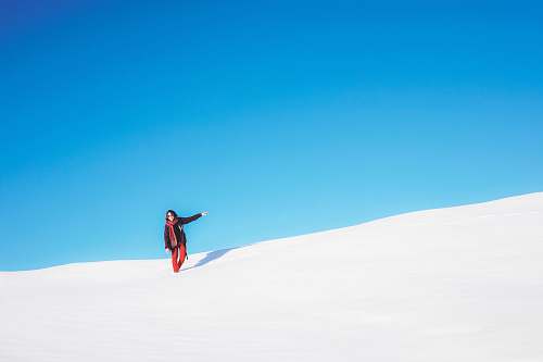 white sand woman standing on white snow field during daytime blue